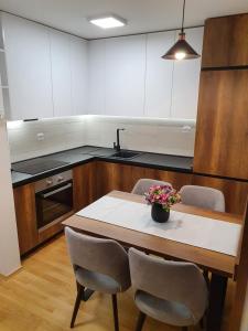Filip&Yana Apartment في مافروفو: مطبخ مع طاولة وكراسي خشبية وطاولة مع زهور