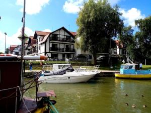 罗威Apartament Sun&Fun - Rowy的两艘船停靠在建筑物前的水面上