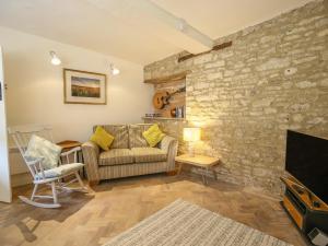 a living room with a couch and a stone wall at 10 George Yard in Burford