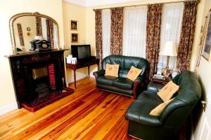 a living room with two leather chairs and a fireplace at Griffin Lodge Guesthouse in Galway