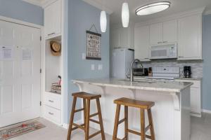 eine Küche mit weißen Schränken und 2 Barhockern in der Unterkunft Vela Villa in Lago Vista