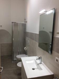 een badkamer met een wastafel, een toilet en een spiegel bij Casa Giò in Cisternino