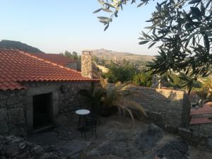 a stone house with a table and a chair at Casa da Vila in Sortelha