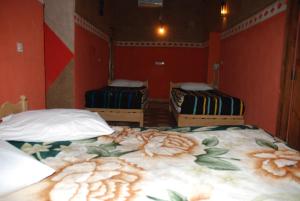 two beds in a room with red walls at Paradise in the southern desert Morocco in Tamegroute