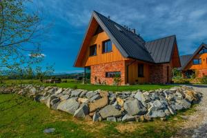 a house with a rock wall in front of it at Białczańskie Bacówki in Białka Tatrzańska