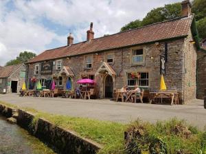 a building with tables and umbrellas in front of it at Plume of Feathers in Blagdon