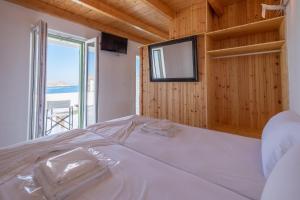 un letto bianco in una stanza con una grande finestra di Lorenzo Studios and Suites Paros a Naoussa
