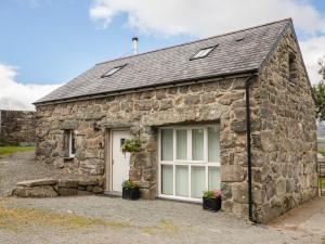 a stone cottage with a white door and windows at Hendre Cottage in Trawsfynydd
