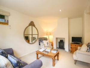 a living room with a table and a mirror at Kettle Cottage in Chipping Campden