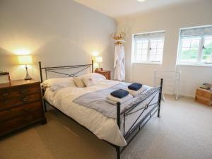 ein Schlafzimmer mit einem Bett, einer Kommode und zwei Fenstern in der Unterkunft Kettle Cottage in Chipping Campden