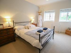 a bedroom with a bed and a dresser and two windows at Kettle Cottage in Chipping Campden