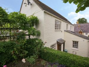 an old white house with a hedge at Kettle Cottage in Chipping Campden
