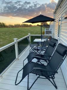 two chairs and a table on a porch with an umbrella at Luxury Holiday Home in Anderby Creek in Anderby