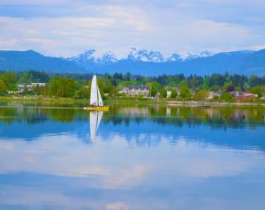 un velero en un lago con montañas en el fondo en Estuary House Reflexology B&B, en Courtenay