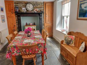 a dining room with a table and a clock on the wall at Heightley House in Tintagel