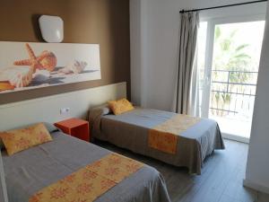una camera d'albergo con due letti e una finestra di Apartamentos Arcadio a El Arenal
