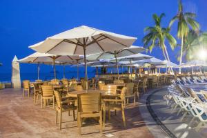 una fila de mesas y sillas con sombrillas en la playa en VILLA PARA 5 Personas 4 adultos y 1 Menor En HOTEL TSORO IXTAPA WIFI GRATIS, en Ixtapa