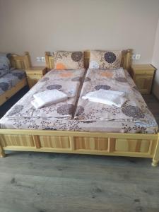 ein Bett mit einem Holzrahmen mit Kissen darauf in der Unterkunft ИВАНЕЛИ in Saparewa Banja