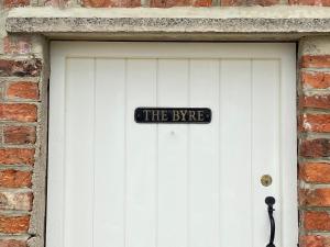 eine weiße Garagentür mit Schild drauf in der Unterkunft The Byre in East Cowton