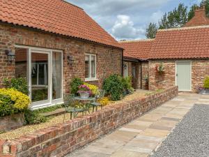 a brick house with a patio with chairs and a table at The Byre in East Cowton