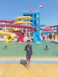 a young boy standing in front of a water park at شاليهات بورتو مطروح فيو بحر Porto Matrouh Sea View Families Only in Marsa Matruh