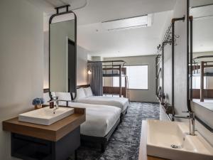 a hotel room with two beds and a sink and a mirror at The Lively Osaka Honmachi in Osaka