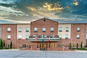 a large brick building with two flags in front of it at Chateau Saint Denis Hotel in Natchitoches