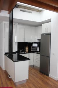 a kitchen with white cabinets and a stainless steel refrigerator at Apartamentos Coronado in Málaga