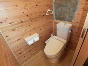 a bathroom with a toilet and wooden walls at Shirahama Meiji Villa in Shirahama
