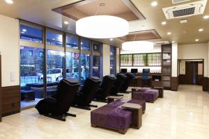 a waiting room with chairs and tables and windows at The Bridge Hotel Shinsaibashi in Osaka