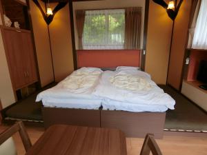 a bedroom with a bed with white sheets and a window at Shirahama Meiji Villa in Shirahama