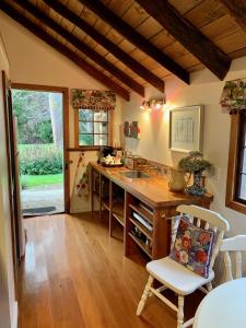 a kitchen with a sink and a desk with a chair at Mill Cottage - boutique accommodation and garden in Akaroa