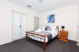 a white bedroom with a bed and a dresser at 4 Bedroom Inner City Townhouse - SLEEPS 9 !! in Wagga Wagga