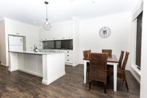 une cuisine avec des armoires blanches et une table et des chaises dans l'établissement Glen’s Inner City Escape - CBD Central, à Wagga Wagga