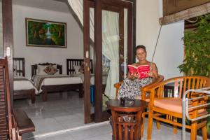 a woman sitting in a chair reading a book at Amed Beach Resort in Amed