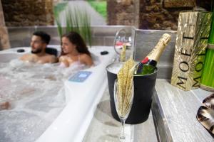 um homem e uma mulher numa banheira com uma garrafa de champanhe em LA VEGUILLA DELUXE JACUZZi em Alhama de Aragón