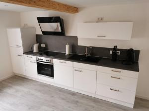 a kitchen with white cabinets and a black counter top at Traumhaftes Apartment zentral in Bad Berleburg in Bad Berleburg
