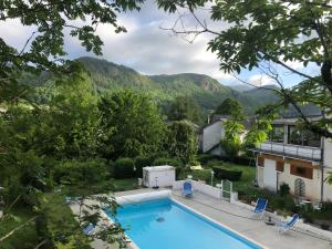 une piscine avec des montagnes en arrière-plan dans l'établissement LOGIS Hôtel Bel Horizon, à Vic-sur-Cère