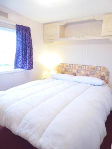 a large white bed in a room with a window at Beachside, Family-friendly, WiFi, 8 berth Caravan 158 in Ingoldmells