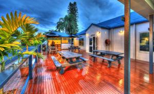 una terraza con mesas de picnic y bancos en una casa en Fraser Coast Top Tourist Park, en Hervey Bay