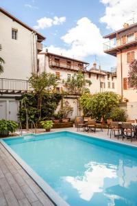 a pool in front of a building with tables and chairs at epOche Hotel Zanella 1889 in Nago-Torbole