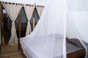 a bed with a mosquito net in a room at BK Homestay, Batukaras in Batukaras