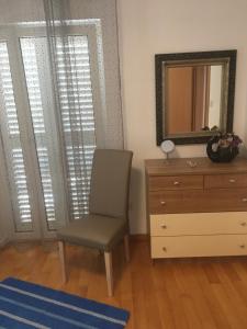 ein Schlafzimmer mit einem Stuhl, einer Kommode und einem Spiegel in der Unterkunft Apartments San Marino in Novi Vinodolski