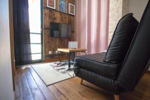 a living room with a black leather chair and a table at Modern & Recycled Guest House in Machico