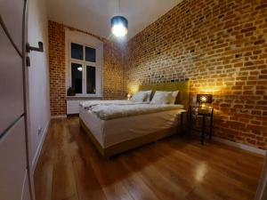 Schlafzimmer mit Ziegelwand und Bett in der Unterkunft Apartamenty Lubin - Loft in Lubin