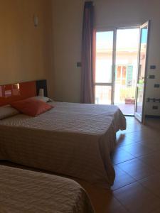 a bedroom with two beds and a sliding glass door at Castellammare Smart Rooms in Castellammare del Golfo