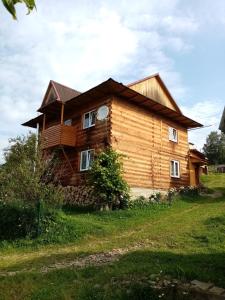 una casa de madera con techo de gambrel en микуличин на долоні, en Mykulychyn