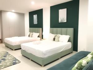 - 2 lits dans une chambre aux murs verts et blancs dans l'établissement KSL City Mall 4-6pax Netflix-SmartTV 65inch, à Johor Bahru