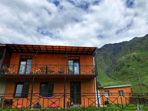 a building with a balcony and mountains in the background at Hotel Elegant in Kazbegi