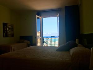 a bedroom with a bed and a window with a view at Castellammare Smart Rooms in Castellammare del Golfo +22 photos